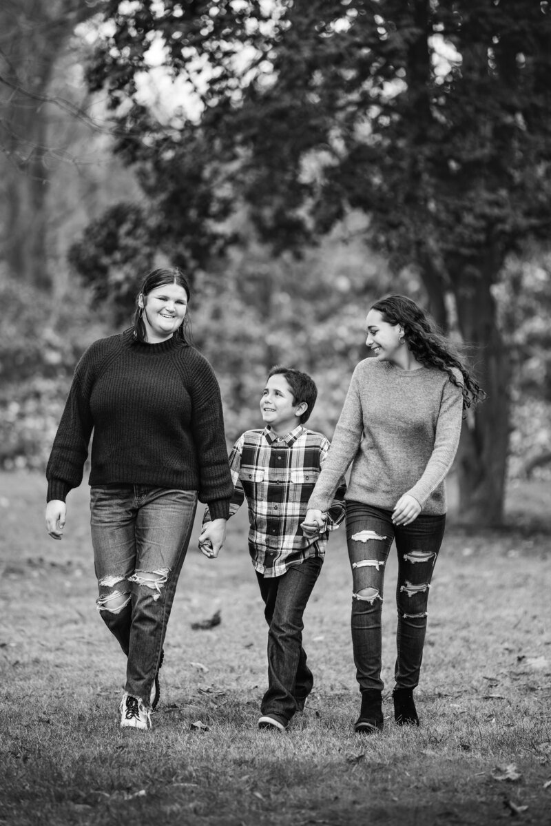 Siblings walking while holding hands and laughing for family photos in Mount Holly, NJ