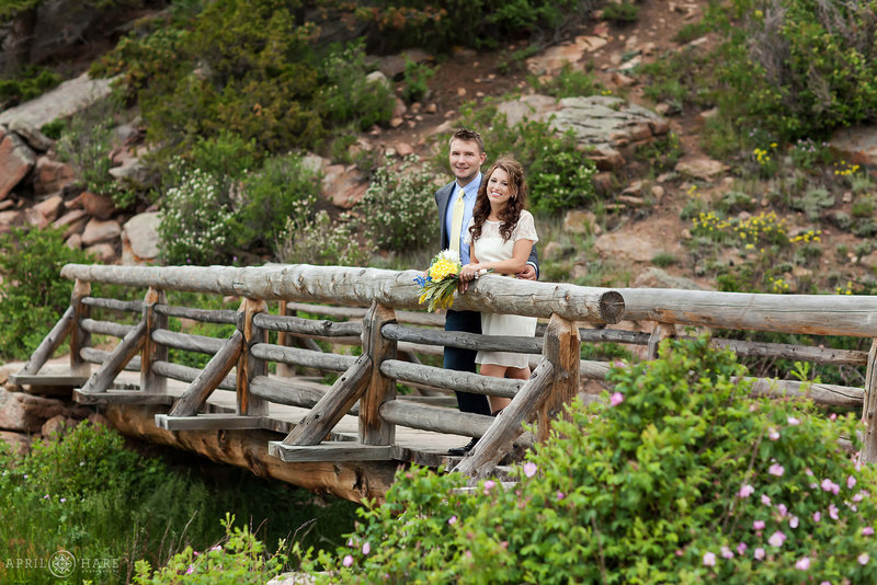 Couple pose on the rustic log wood bridge at Lily Lake in Estes Park Colorado