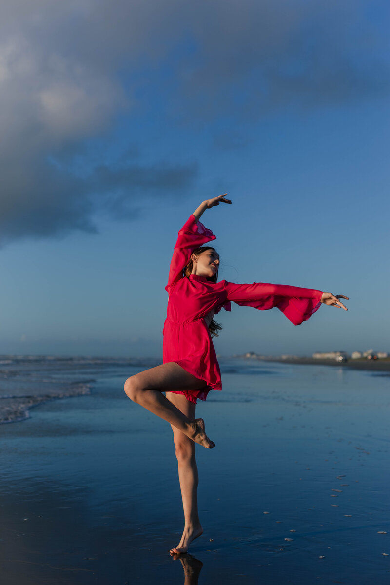 16 year old girl dancing on Galveston beach at sunrise in a pink romper