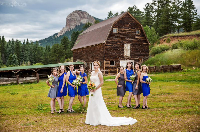 Bride with Bridesmaids wearing bright blue in front of barn at Mountain View Ranch