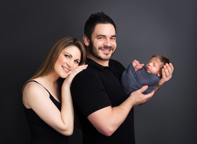 parents posed with baby on grey background