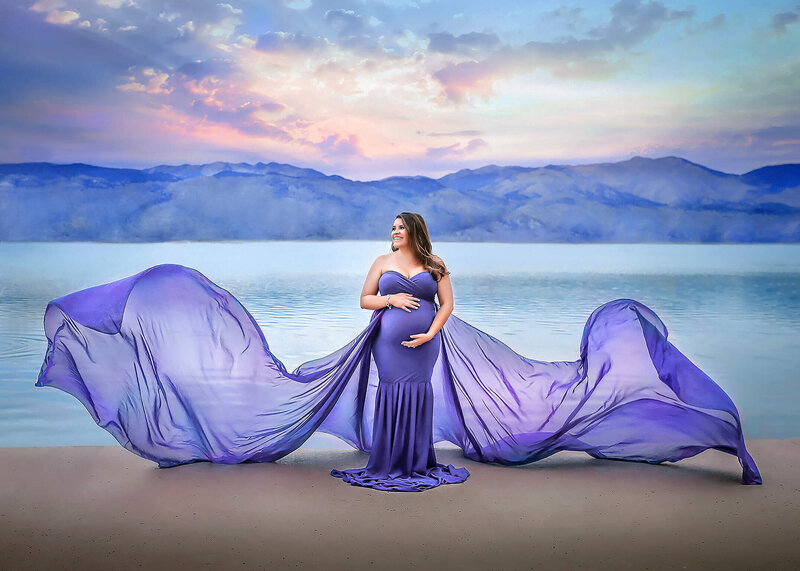 Beautiful momma to be posing in flowy blue dress in front of Coot Lake during her denver family portrait photography session