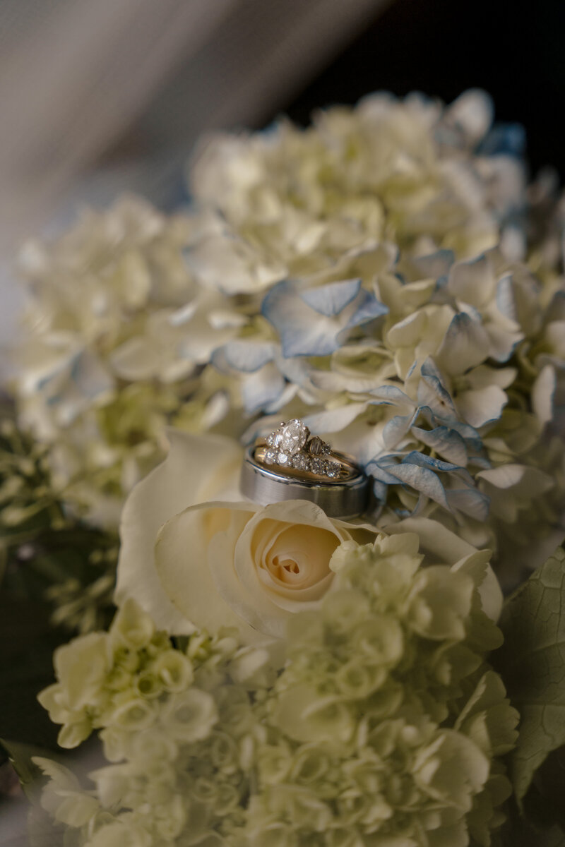 Details of silver wedding rings on a hydrangea bouquet