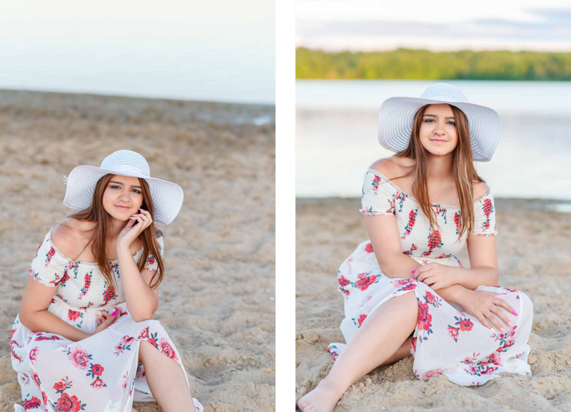 high school senior girl wearing white floral dress sitting on sandy beach in ionia michigan