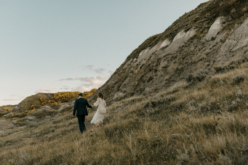 bride and groom walking through grass field