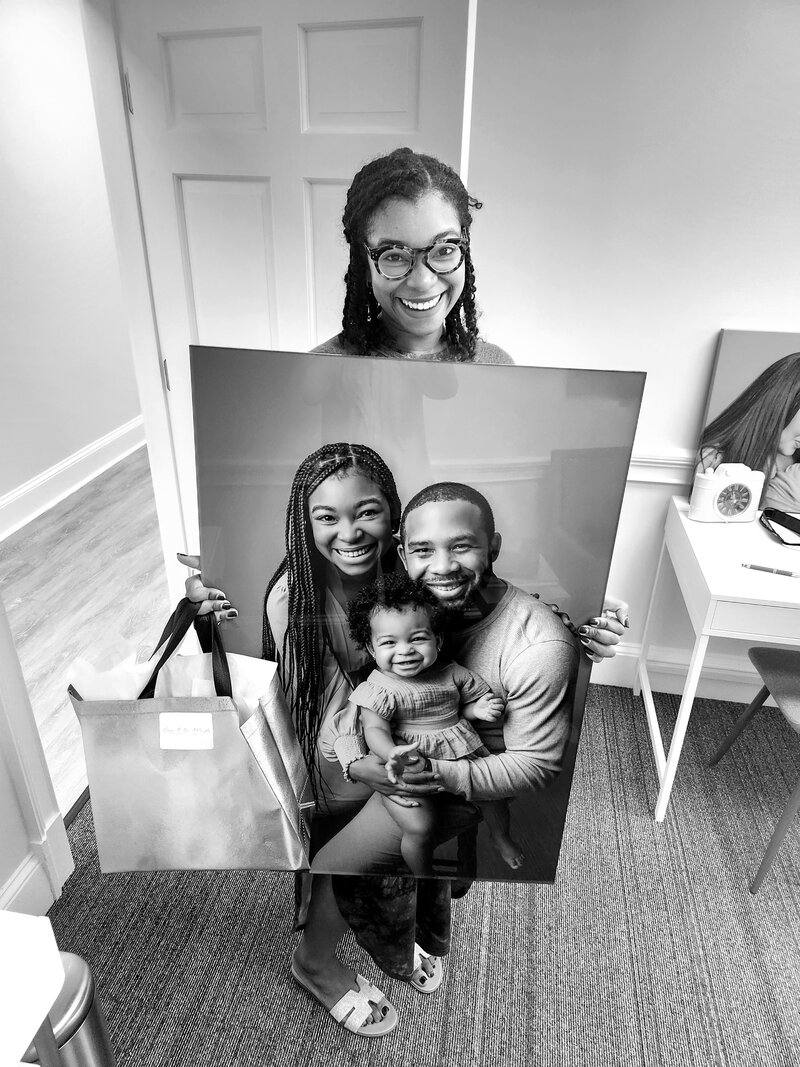Happy client holding up her family portrait artwork at Atlanta newborn photography studio