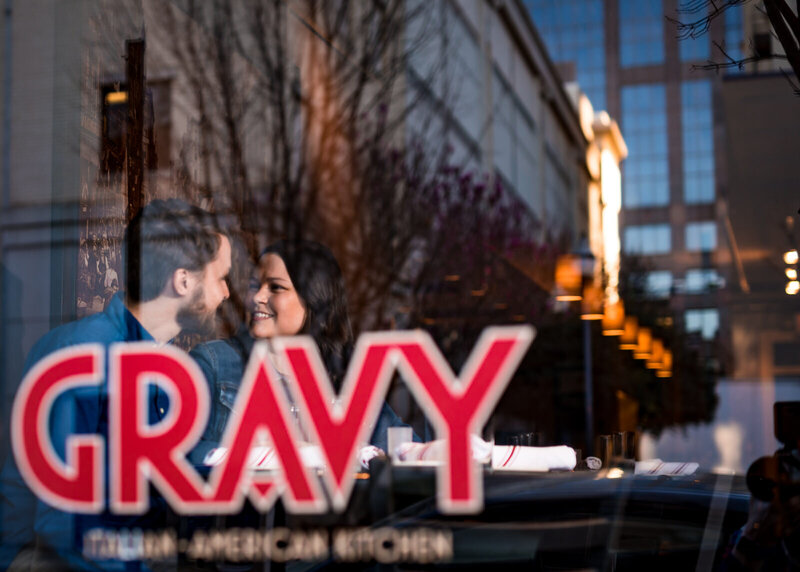 Couple sits at a table inside the window for Gravy, a restaurant in Downtown Raleigh