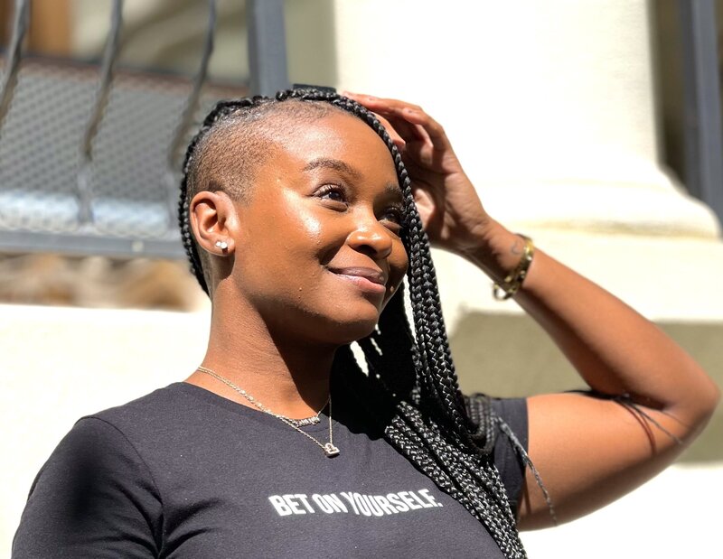 Kayla Butler looking into the distance wearing a  black t-shirt that reads "bet on yourself".