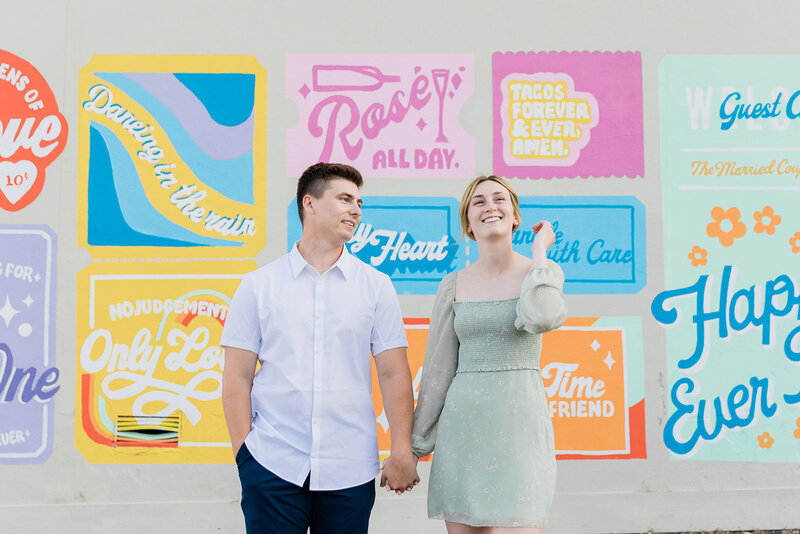 Couple standing in front of colour wall smiling