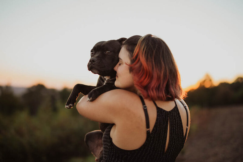 Girl holding her dog during sunrise
