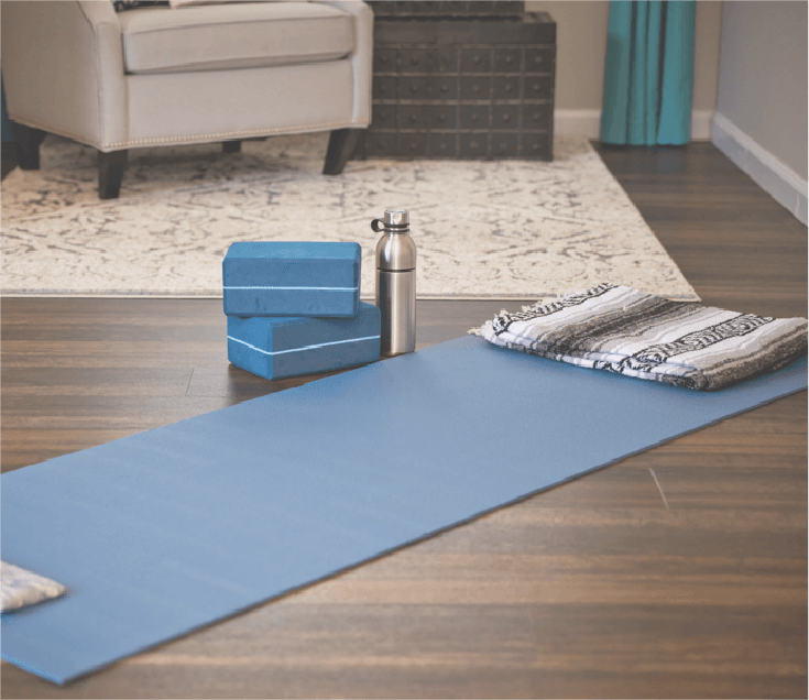A blue yoga mat, block, and water bottle laying in the yoga studio