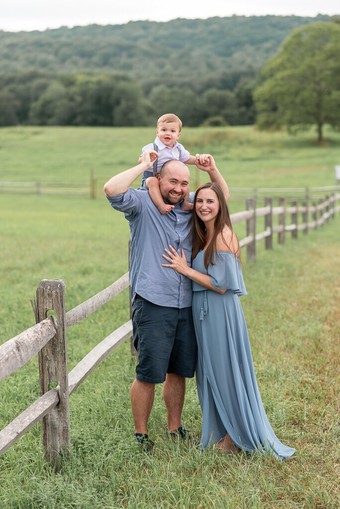 Parents holding young son and smiling in field at sunset in Simsbury, Connecticut | Sharon Leger Photography | CT Newborn & Family Photographer, Burlington, CT