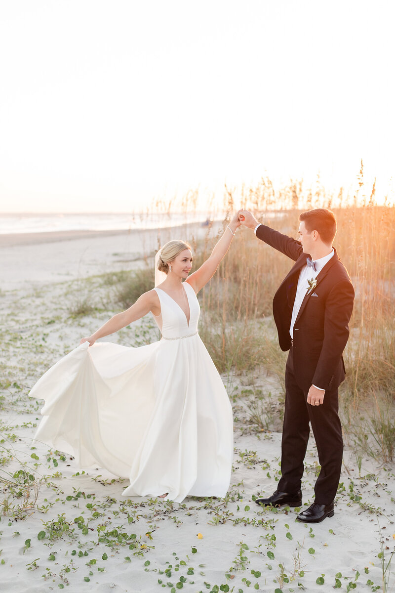 groom twirling bride on beach