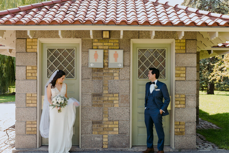 bride and groom standing in front of outdoor bathroom signs  in Ottawa