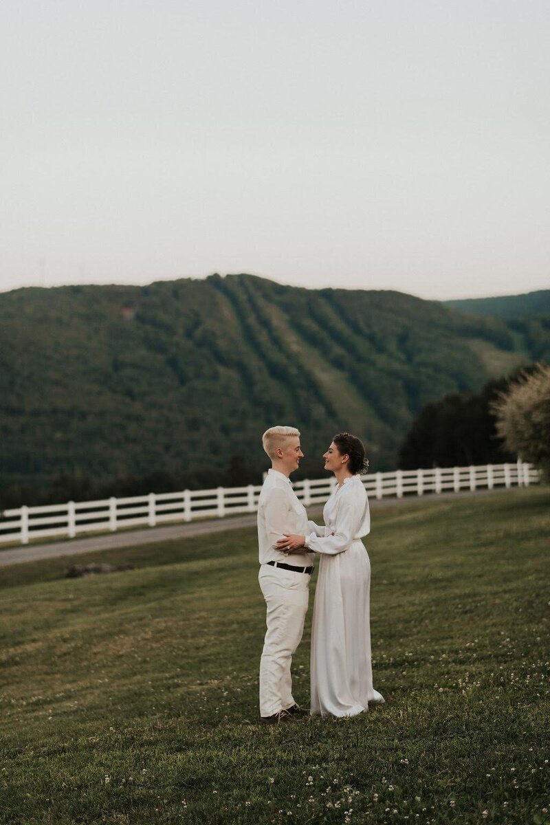 Couple standing in a field looking at each other, Unique Melody Events & Design (New England Wedding Planners) helped with this wedding