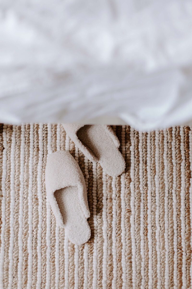 white slippers on the carpet next to bed as self care stock photos