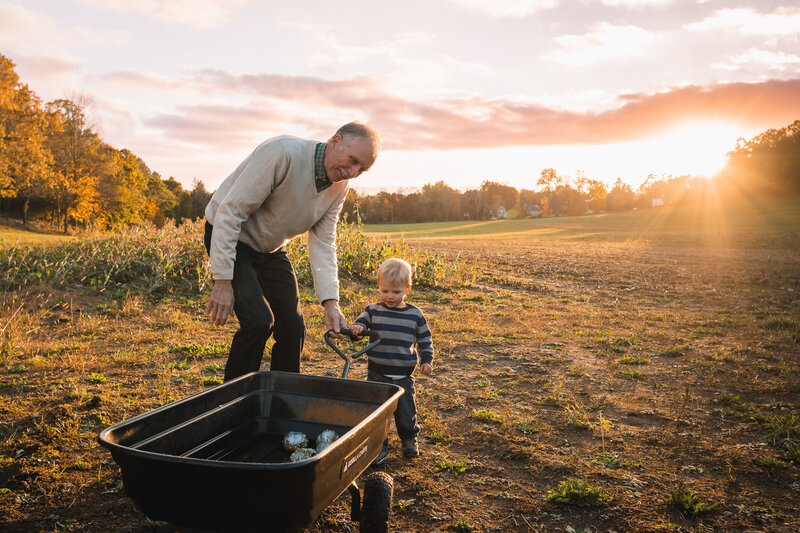 grampa and grandson with wagon in field at sunset