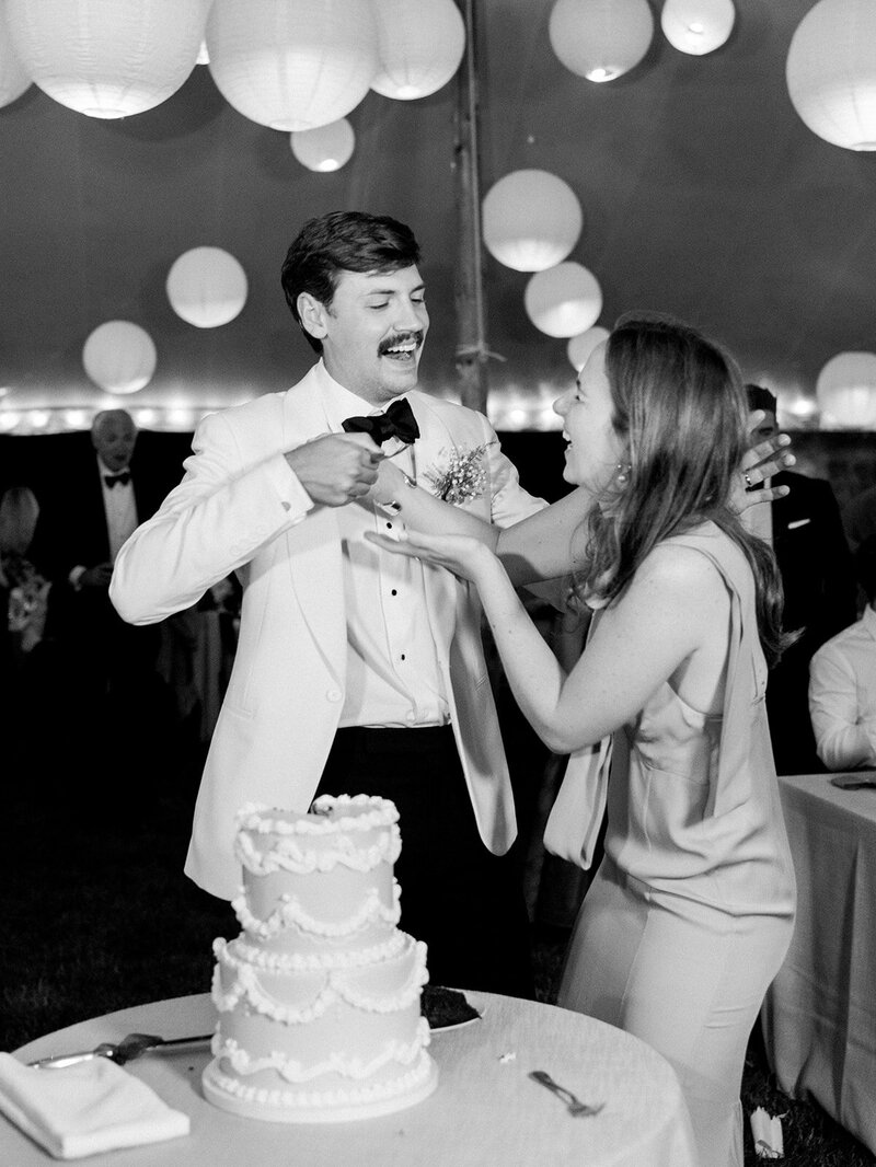 The groom is feeding the bride cake and they are laughing and enjoying the moment.