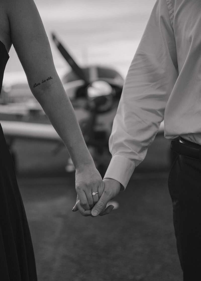 black and white photo of bride and groom holding hands with engagement ring photos