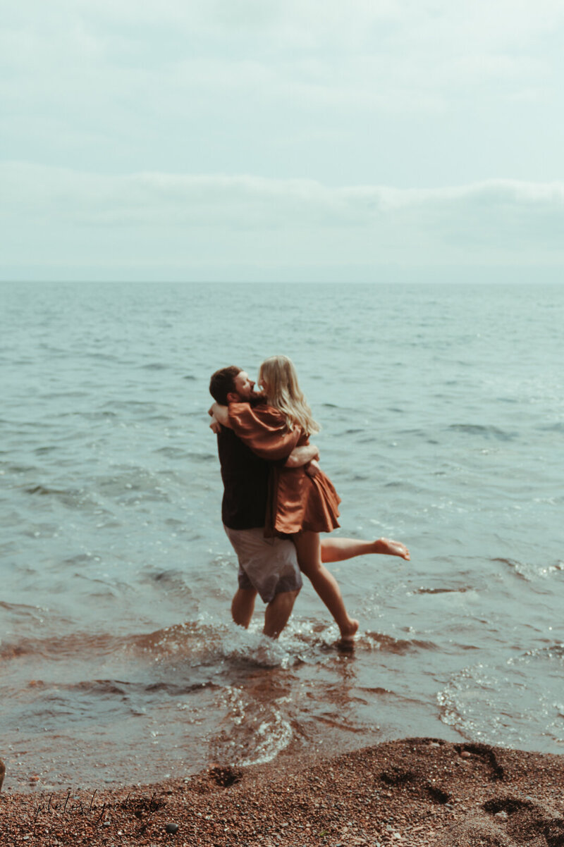 a couple kissing on the shore of lake superior