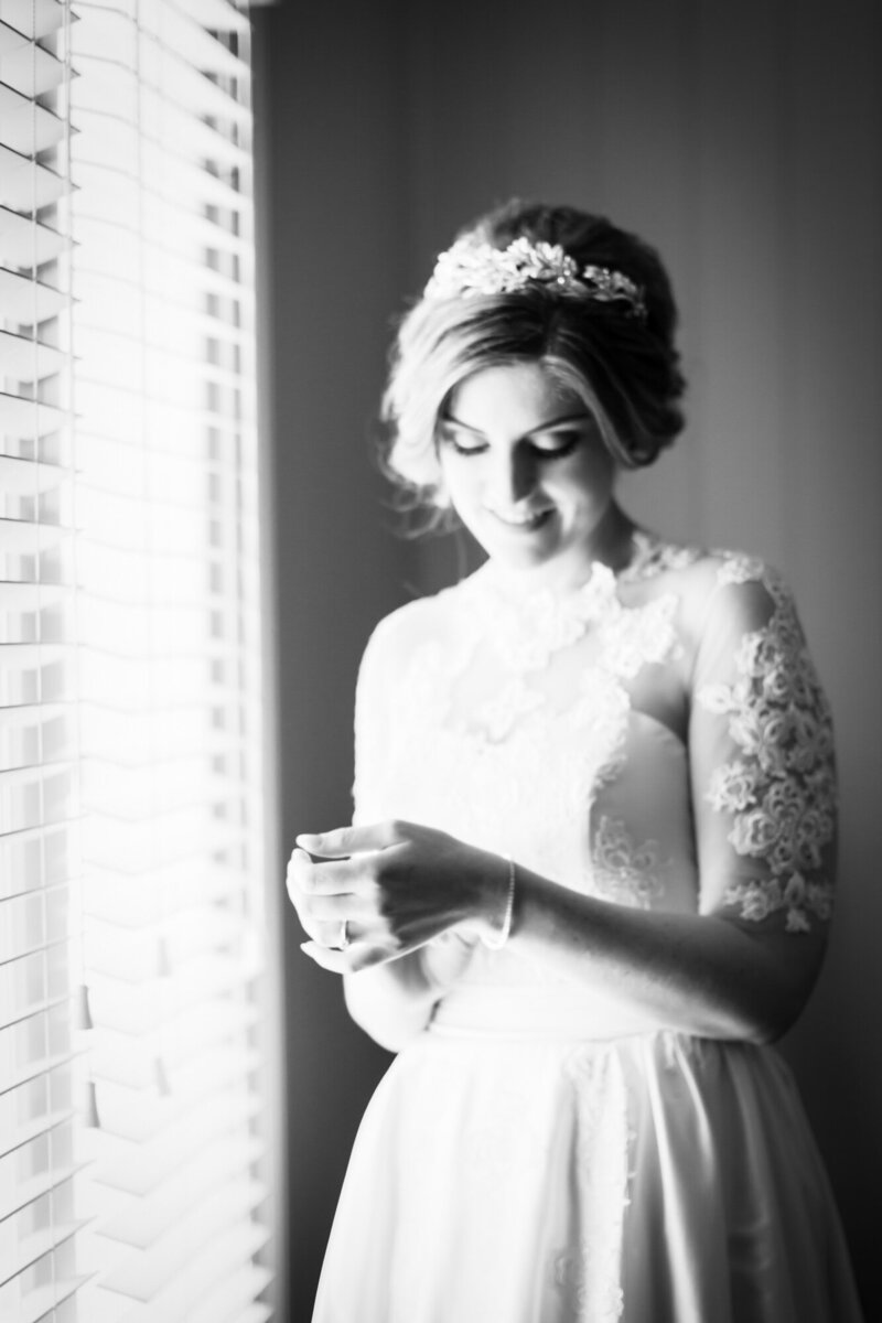 Bride on the side of the window light looking at her hands