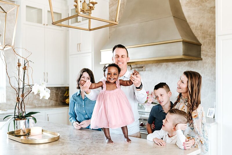 family of 6 playing with newly adopted daughter in kitchen