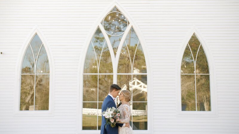 Husband and wife together in front of large farmhouse chapel windows