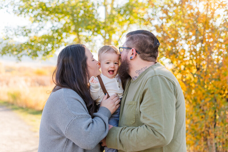 A mom and a dad kiss their baby at a nature park in Bozeman, Montana by Laramee Love Photography