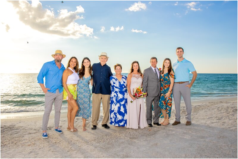 A family wedding photo on the beach at sunset