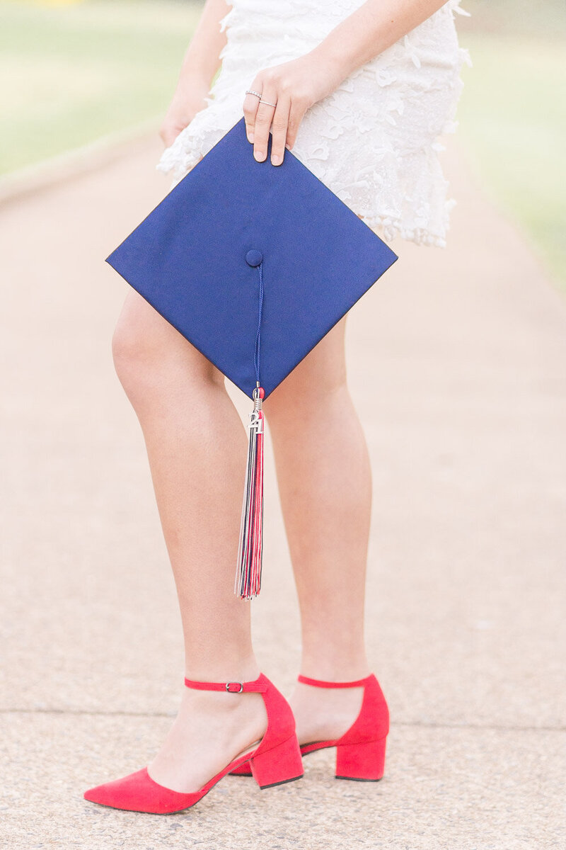 high school girl wearing red shoes holding graduation cap during senior photos in Loudoun County, VA