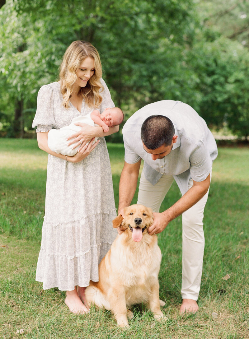 New parents snuggle their newborn and their dog during a Raleigh. newborn session. Photographed by Raleigh newborn photographer A.J. Dunlap Photography.