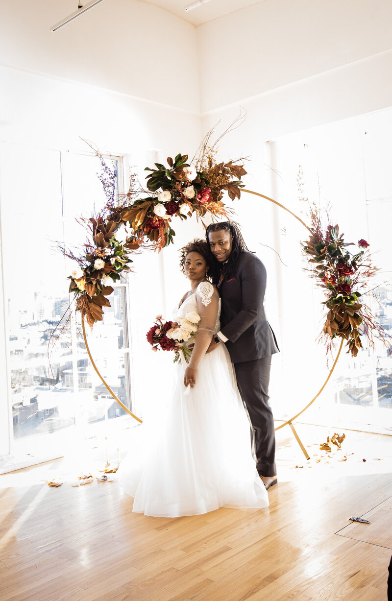 Beautiful light and airy photo of bride and groom next to an amazing floral arch