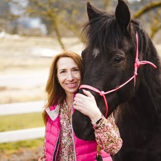 Seattle Real Estate agent Brenda Morris wearing a pink hoody standing next her horse