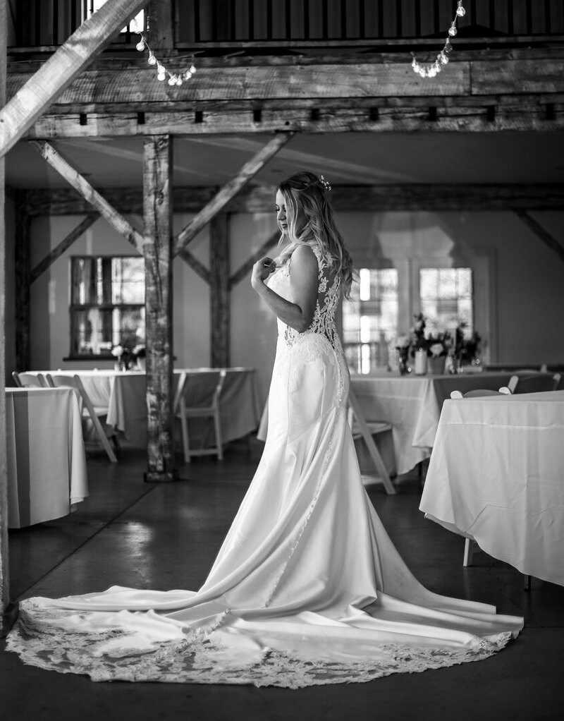 Solo portrait of bride standing in the barn set up for her Quincy Cellars wedding rception