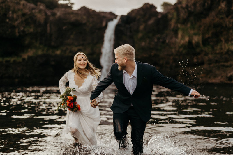 Down-to-earth wedding bride and groom in waterfall with organic florals