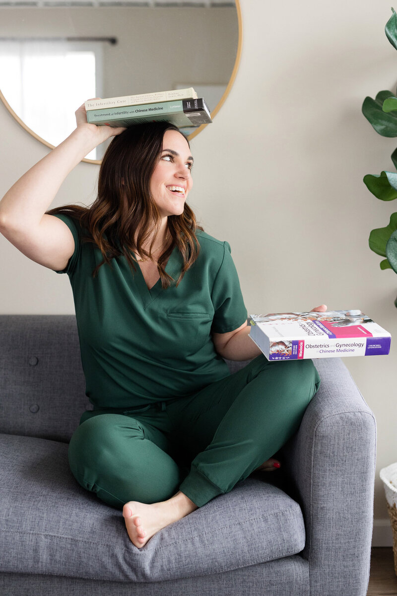 Jamie playfully holding a fertility and women's health book on her head