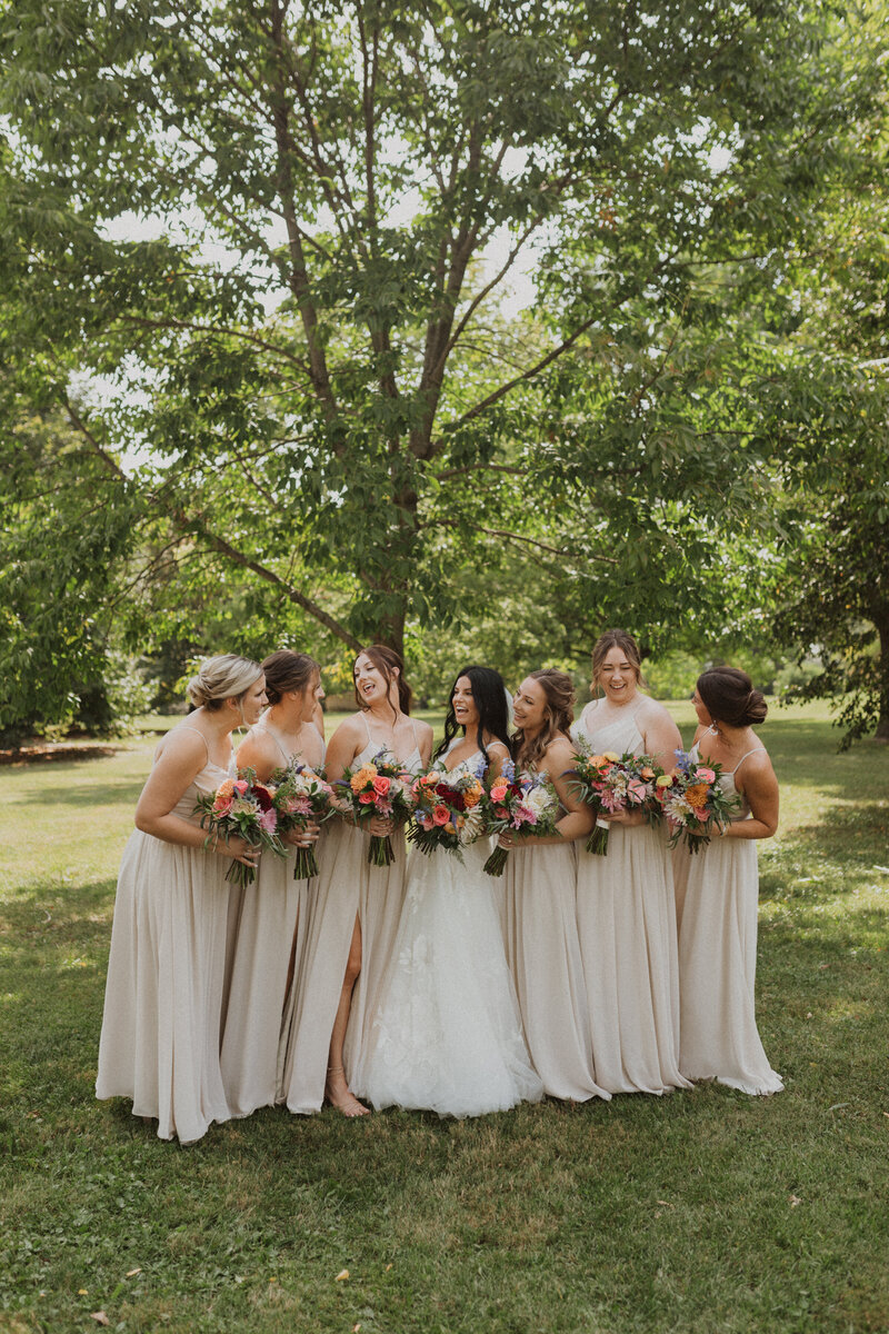 bride and bridesmaids wearing long champagne dresses laughing at each other