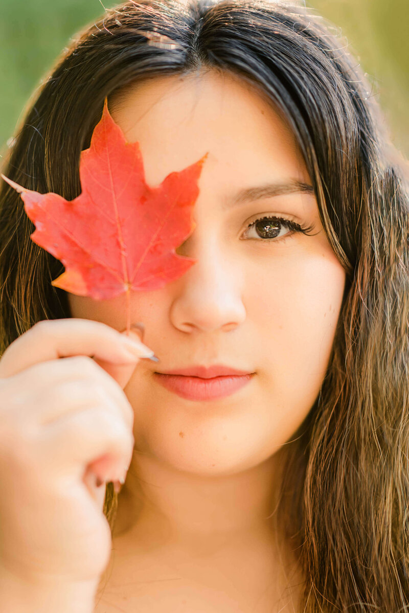 Portrait of a high school senior girl holding a red leaf up to her face
