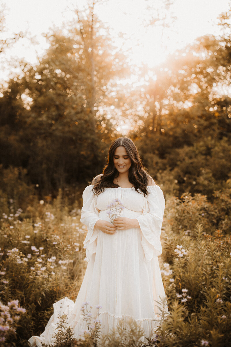 Pregnant mother in a while dress looking ethereal in a Southeaster Wisconsin wildflower field.