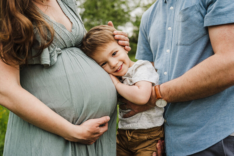 toddler boy lays head on moms pregnant stomach during boston maternity photo session