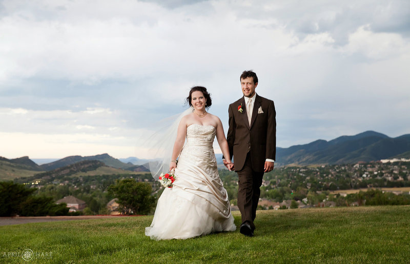 Couple poses on front grassy lawn at The Manor House with views of the Front Range behind them
