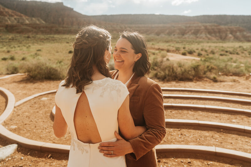 Two bride embrace one another in the middle of the mountains of Zion National Park