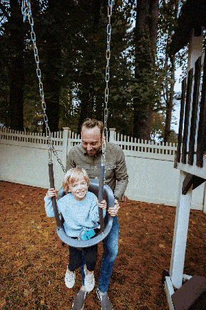 Dad pushes son on swing in backyard at home in Chappaqua