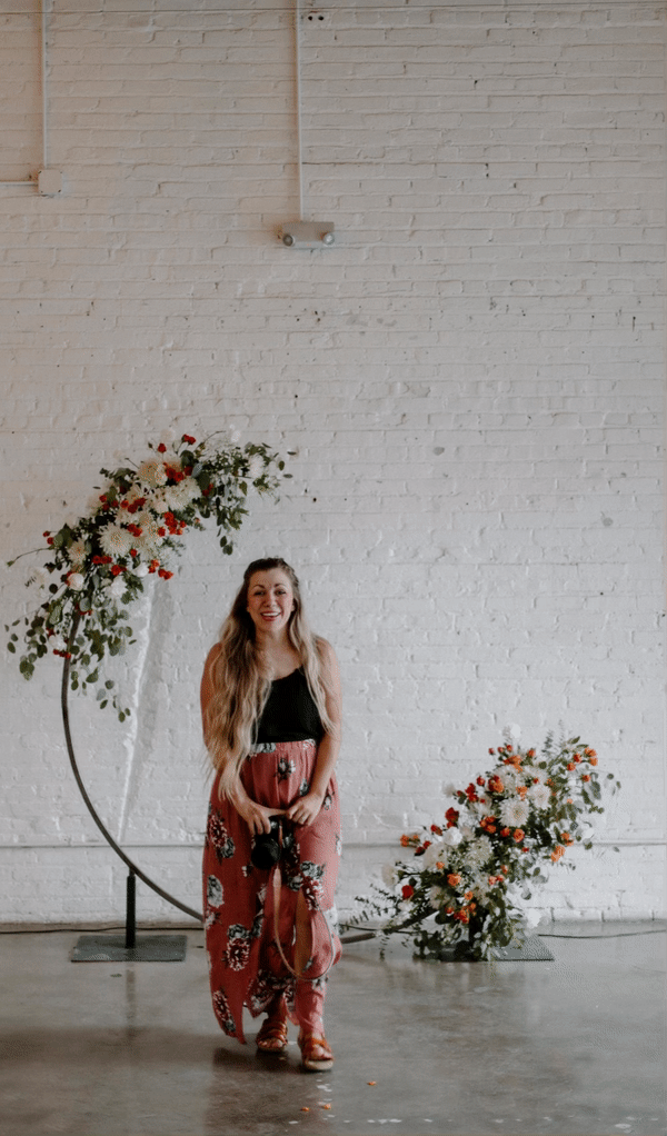 Nikayla posing beside a flower arch for a wedding