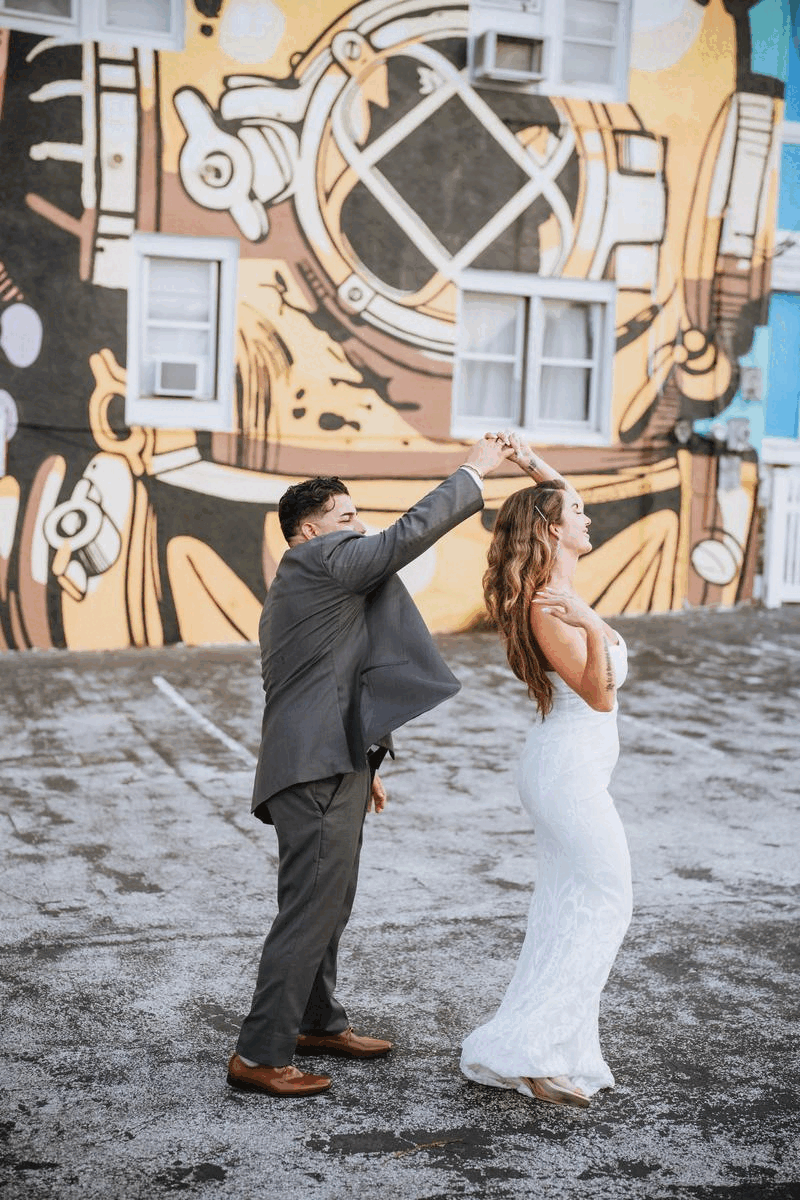 bride and groom dancing in front of graffiti
