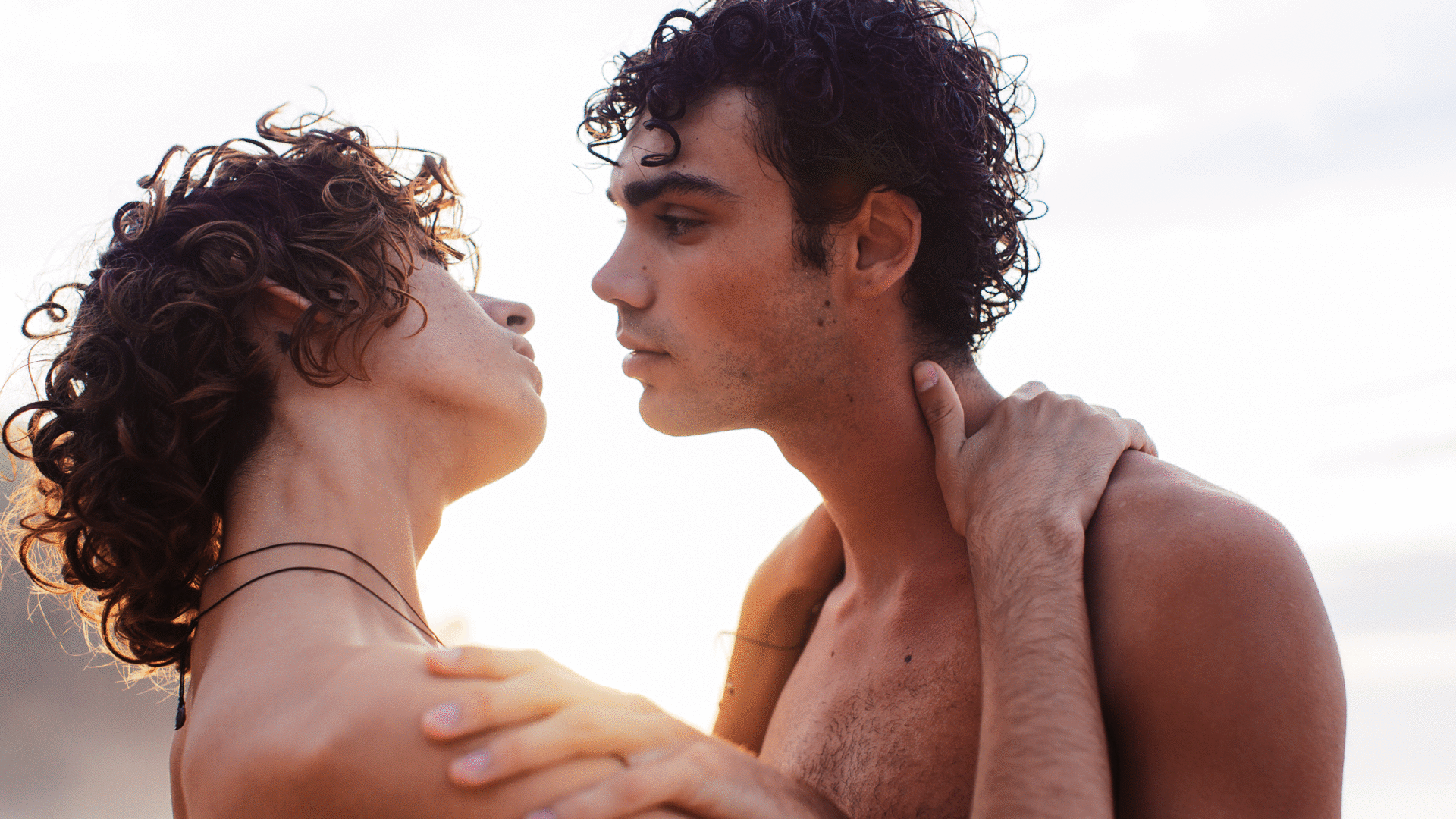 Gif of a homosexual couple smiling and kissing at sunset on the beach.