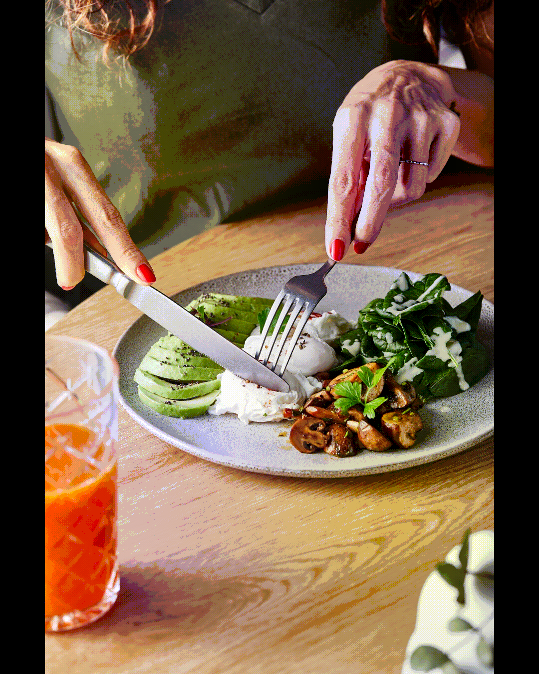 GIF of a poached egg being cut open on a plate with mushrooms, spinach, and avocado.