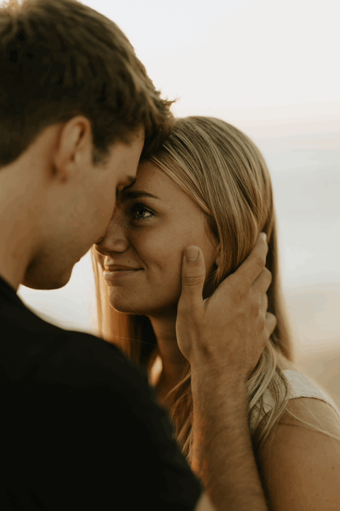 A GIF of a man caressing his girlfriend's cheek while she smiles and closes her eyes