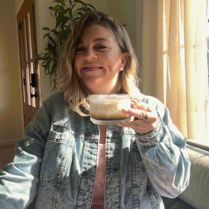 GIF of Mollie Mason smiling holding a clear mug of coffee
