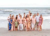 A big family poses on the sands of Ocean Isle Beach, dressed in a mix of pastels and neutrals. The ocean waves add a lively touch, capturing the warmth and connection of a multi-generational reunion. Perfect for artistic family photography in Wilmington, NC.
